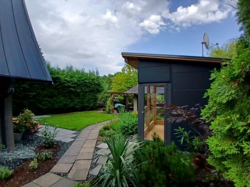 Gondozott kert szaunával és háttérben a fedett terasszal