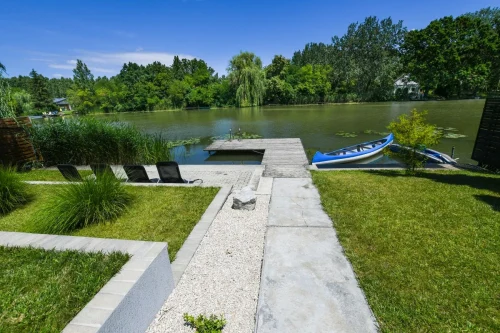 Stég, a négyszemélyes kenuval és a kiépített parton található napozóágyakkal