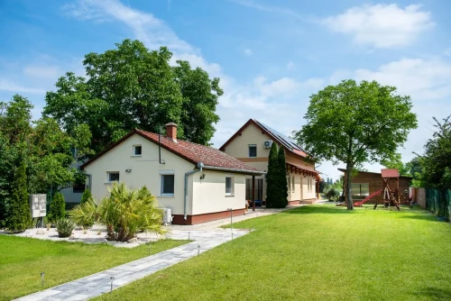 A hátsó kis épület és a nagy épület nagy parkosított kerttel, játszótérrel