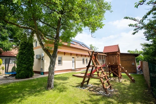 Csúszdás, homokozós rönkfa játszótér és trambulin a kertben