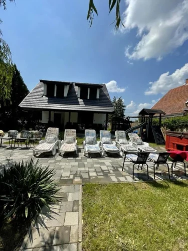 Kert a vízpart felől, napozóágyakkal, jacuzzival és játszótérrel