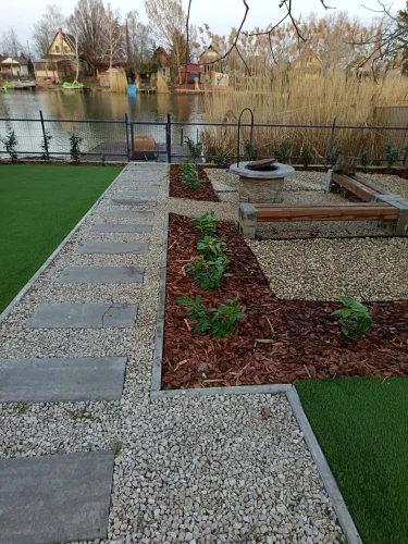 Rendezett udvarban hangulatos szalonnasütő hely vízparti kilátással