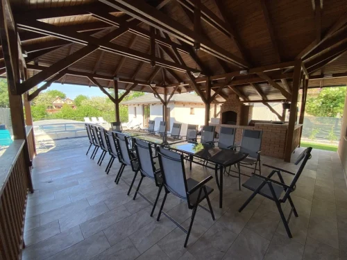 Nagy fedett terasz étkezőasztallal, hangulatos nyári konyhával