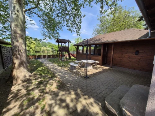 Négy oldalról elkerített nyaraló sütögetővel, rönkfa játszótérrel