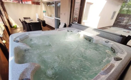A hatszemélyes jacuzzi és kényelmes kerti bútorok is a kikapcsolódást szolgálják a teraszon