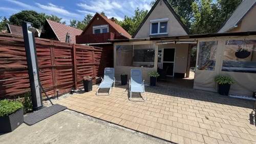 Nyaraló a vízpart felől: kerti tusoló, napozóágyak, fedett terasz