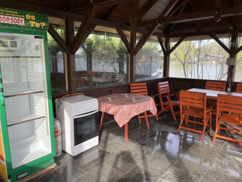 Hűtővel, gáztűzhellyel és kerti bútorral felszerelt, vízpartra néző fedett terasz