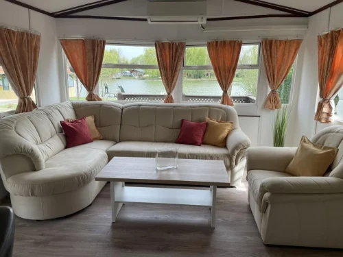 Tv-vel felszerelt nappali, kényelmes ülőgarnitúrával, kilátással a vízpartra