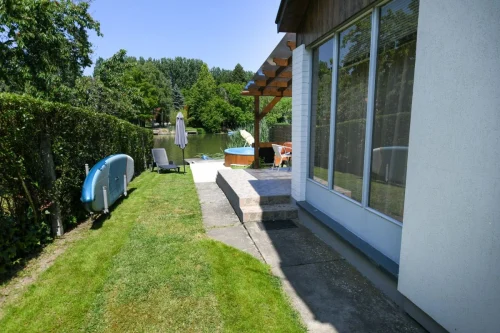 SUP és napozóágyak a gondozott vízparti nyaraló kertjében